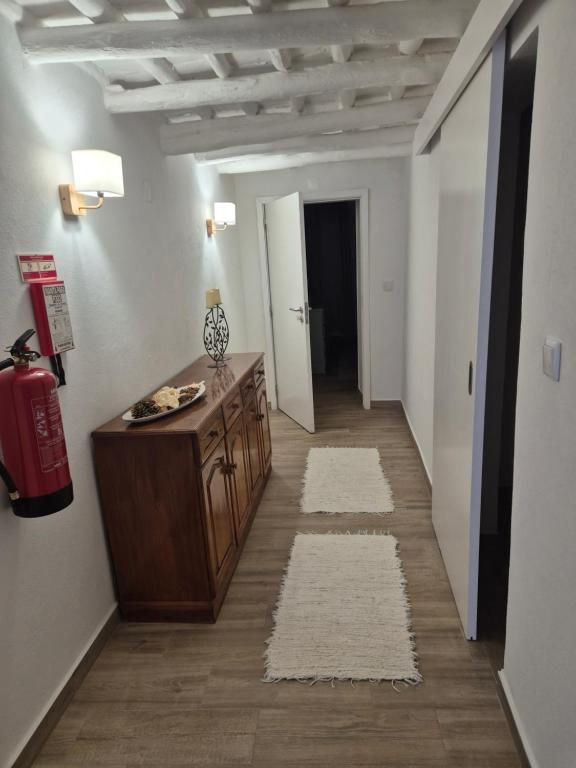 Corredor com teto de vigas brancas e cómoda antiga de madeira