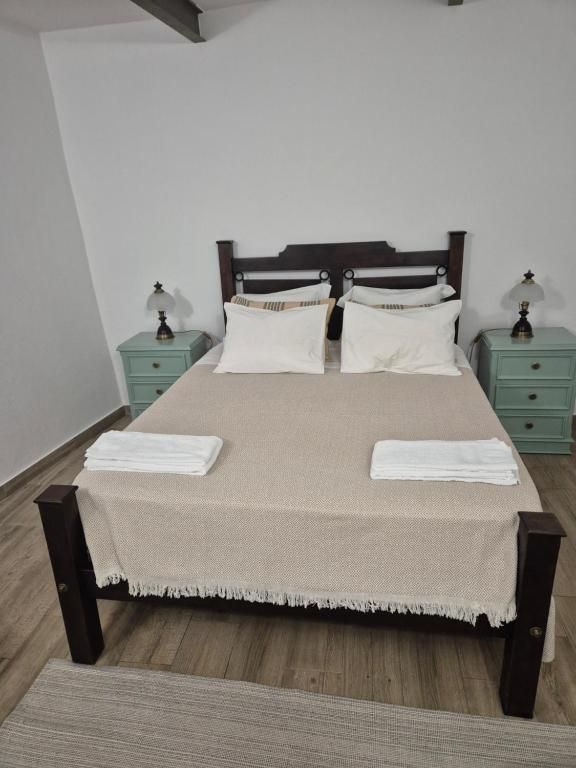 Quarto de casal com cama de madeira escura e mesas de cabeceira verde-água